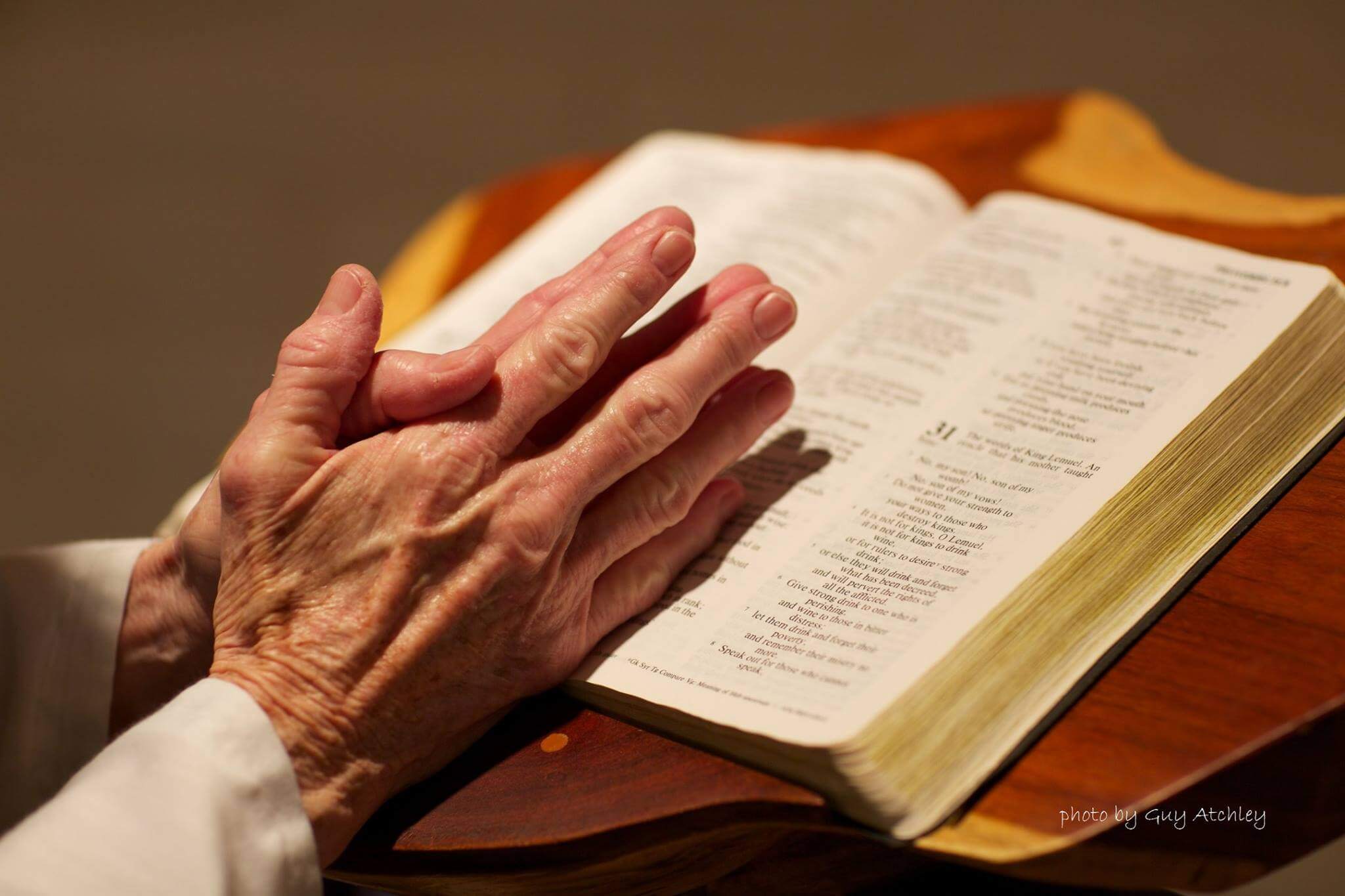 A nun is praying with a bible in an abbey