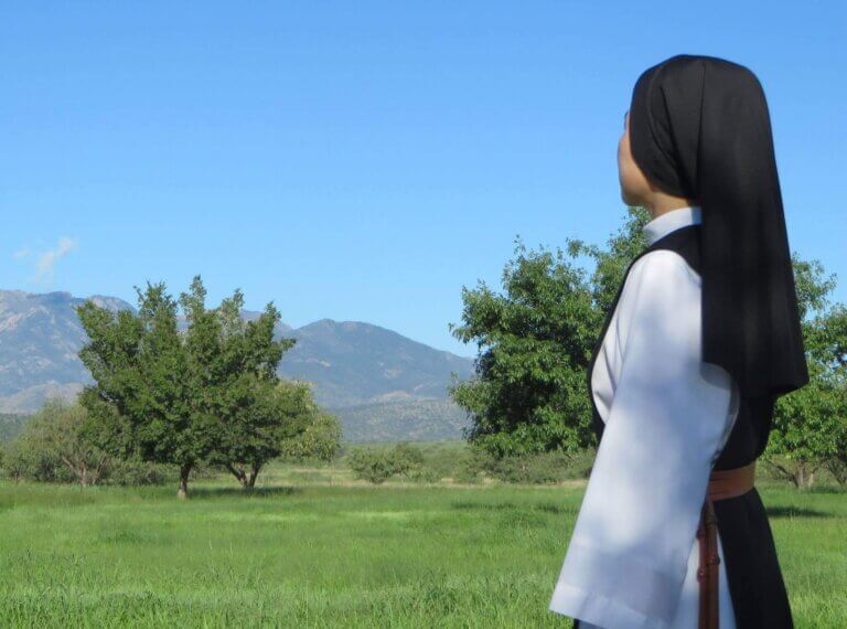 A nun is reflecting on the landscape in Arizona outside of an abbey